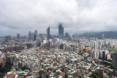 Aerial view of cityscape against cloudy sky