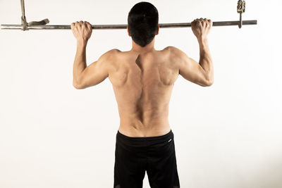 Rear view of shirtless man against white background