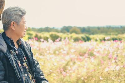 Side view of woman looking at camera on field against sky