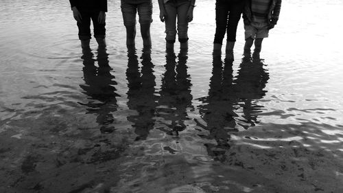 Midsection of friends standing in sea at beach