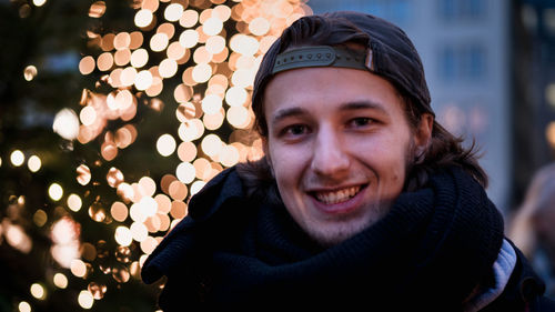 Close-up portrait of smiling man in illuminated city during winter