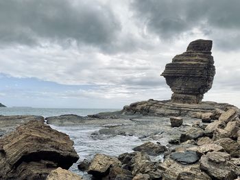 Rock formation on beach against sky