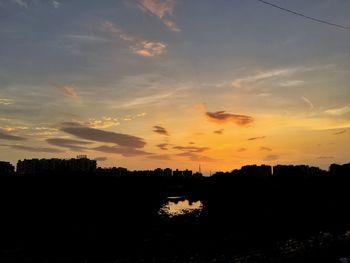 Silhouette trees on landscape against sky at sunset
