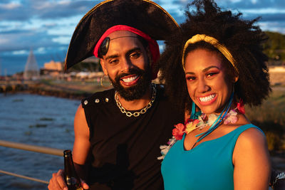 Portrait of smiling friends standing against sea