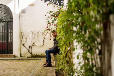 Side view of girl sitting on footpath