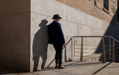 Full length of adult man in hat and suit standing on street against wall. madrid, spain