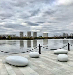 Modern buildings by lake against sky in city