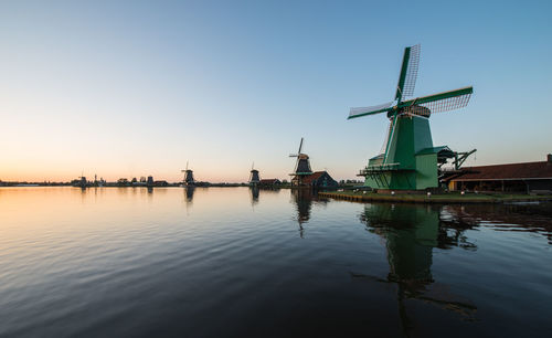 Traditional windmill by river against sky