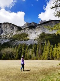 Rear view of man standing on mountain against sky