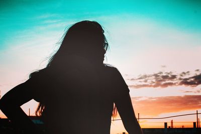 Rear view of silhouette woman standing against sky during sunset