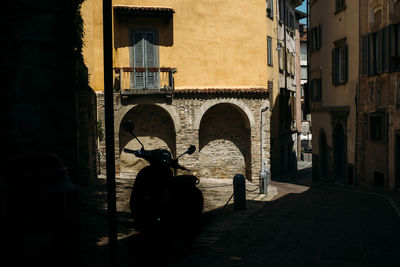 Silhouette motorcycle parked on street against building in city