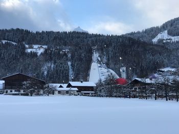 Houses on snow covered landscape against sky