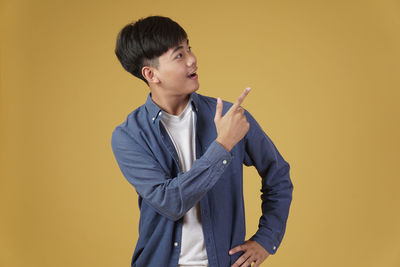 Boy looking away while standing against yellow background