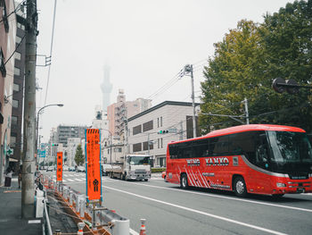 Vehicles on road against sky in city