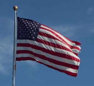 Low angle view of american flag against blue sky