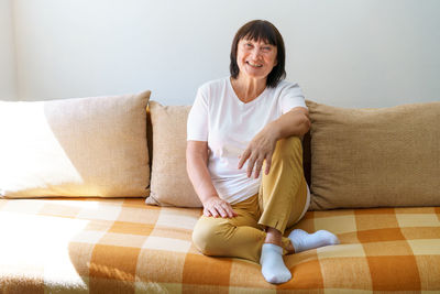 Happy mature woman relaxing on sofa at home in living room. portrait