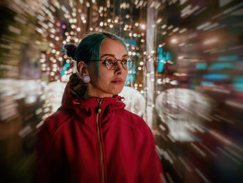 Close-up of young woman wearing eyeglasses while standing outdoors at night