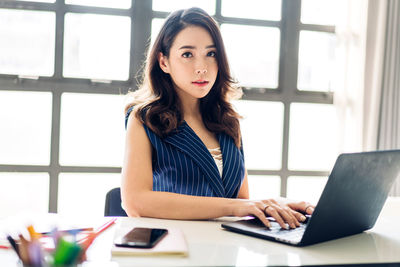 Portrait of young woman using mobile phone at home