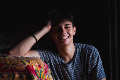 Portrait of cheerful young man sitting by bed at home