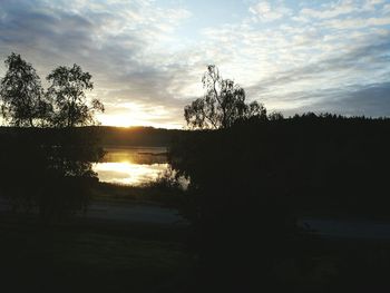 Silhouette trees by lake against sky during sunset