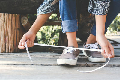 Low section of woman wearing shoes on boardwalk