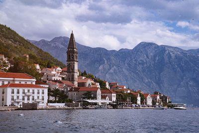 Buildings by lake against sky