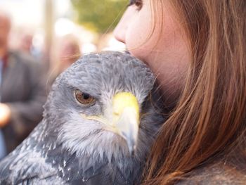 A young woman hugs a bird of prey