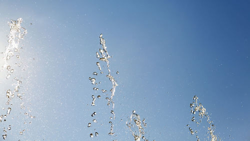 Low angle view of water splashing against blue sky