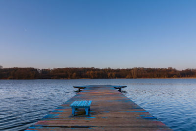 Pier over lake against clear blue sky