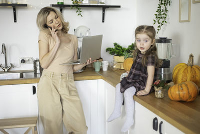 Mother talking on phone while standing at kitchen