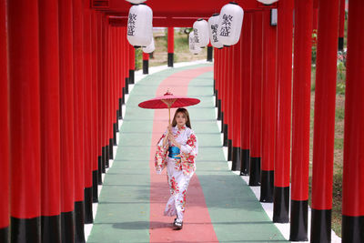 Full length of woman standing by red building