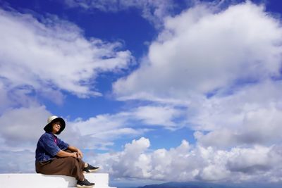 Side view of woman sitting on the stairs against sky