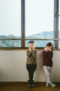 Full length of a girl standing against window