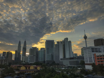 Buildings in city against cloudy sky during sunset