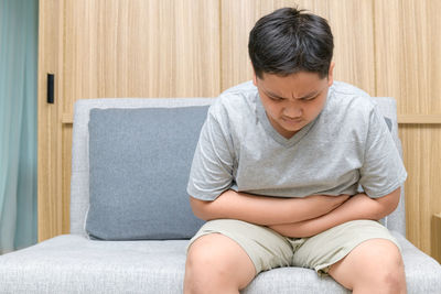 Midsection of man sitting on sofa at home