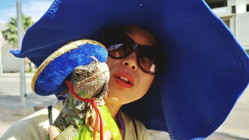 Close-up of young woman with iguana wearing hat