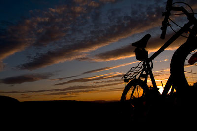 Silhouette of bicycle on field during sunset