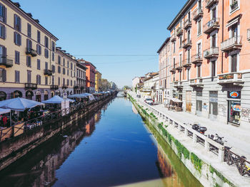 Canal amidst buildings against clear sky in city