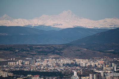 Aerial view of townscape and mountains against sky