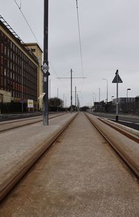 Surface level of railroad tracks by street against sky