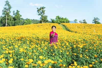 Portrait of woman standing in marigold field