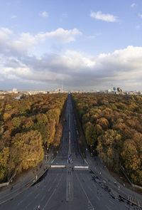 Road amidst trees against sky in city