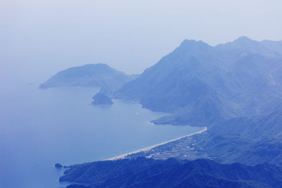 Aerial view of sea and mountains against clear sky