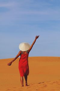 Full length of woman standing on sand at beach against sky