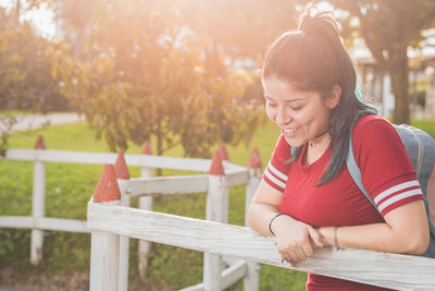 Portrait of young woman sitting on railing