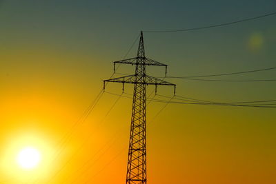 Low angle view of silhouette electricity pylon against sky during sunset