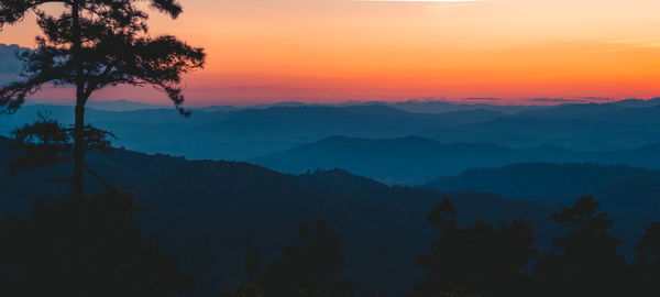 Scenic view of silhouette mountains against orange sky