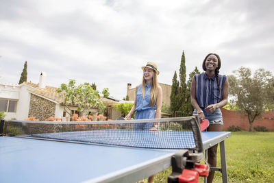 Happy women playing table tennis at yard