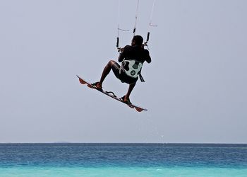 Rear view of man kiteboarding over sea against sky