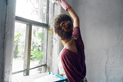 Rear view of woman standing against window